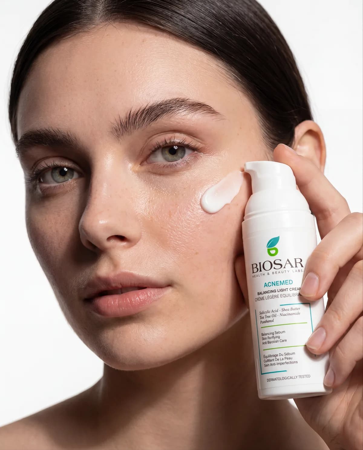 A woman applying BIOSAR Acnemed treatment cream to her cheek